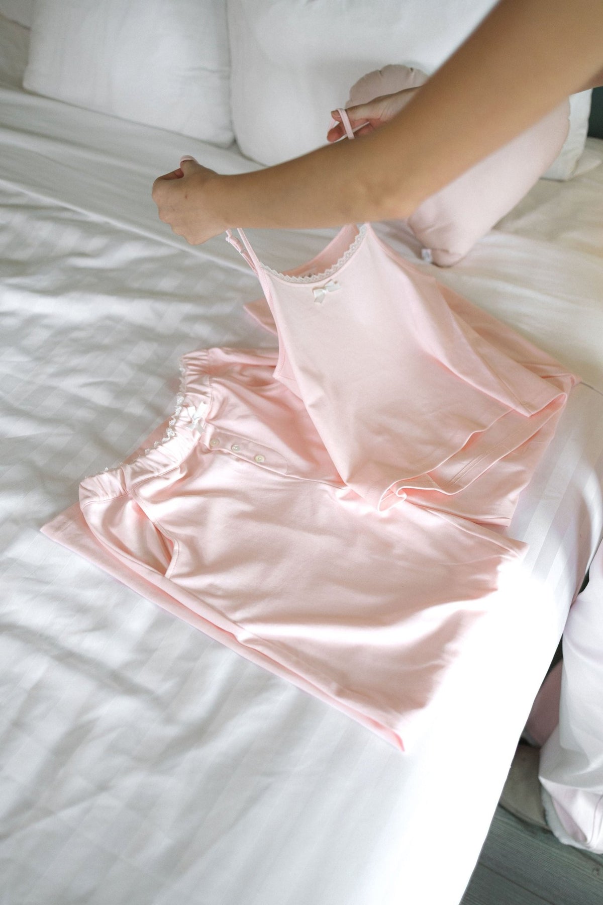 The Raspberry cotton pajama set laid flat on white bedding, showing the folded pants and camisole top