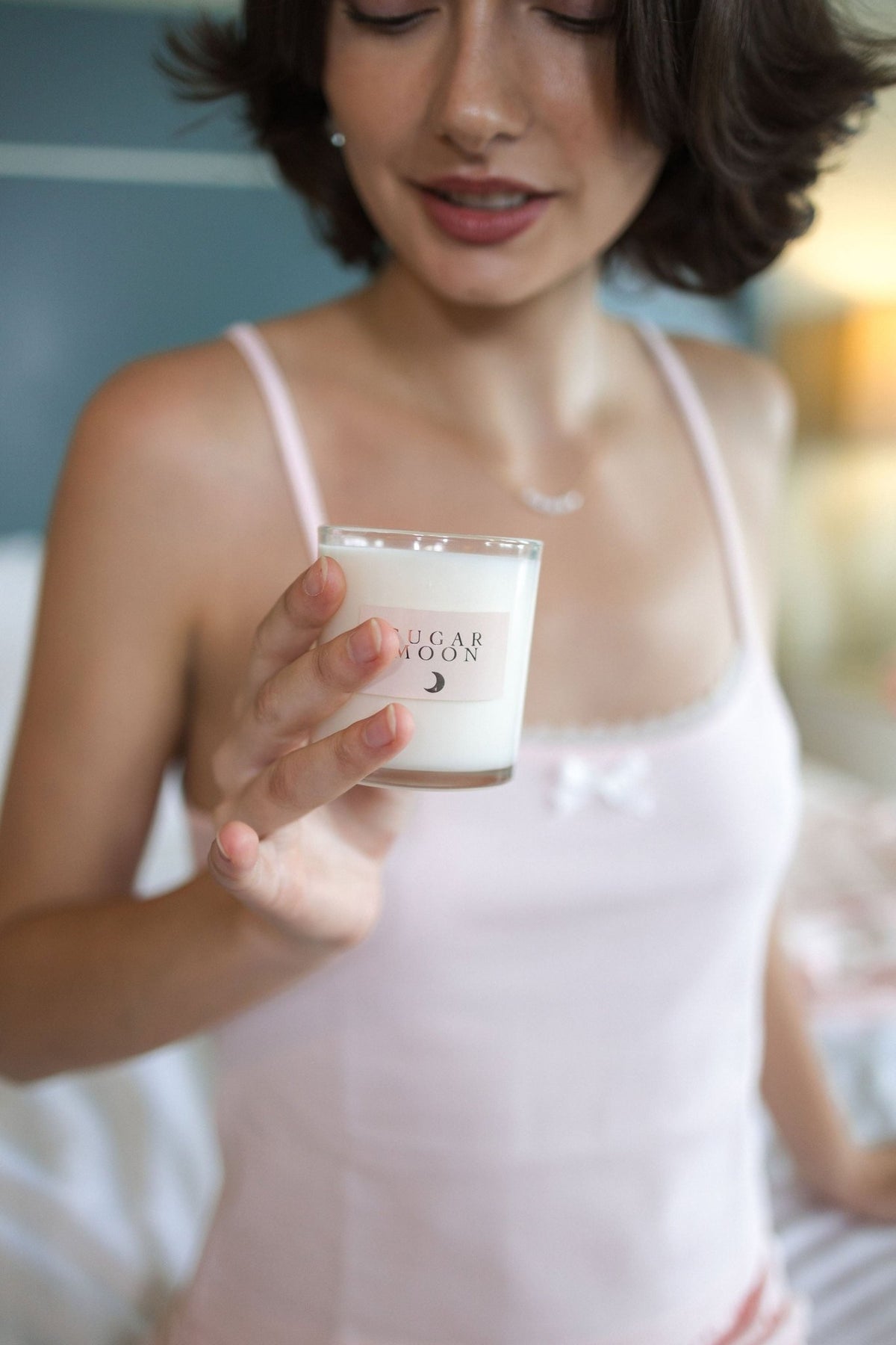 The Raspberry cotton pajama top in blush pink, holding a lit candle in the evening