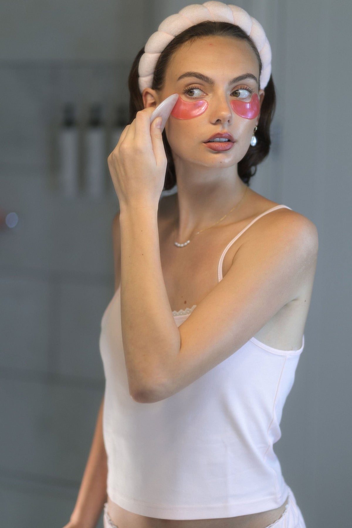 The Raspberry cotton pajama top worn in a bright bathroom during an evening skincare routine